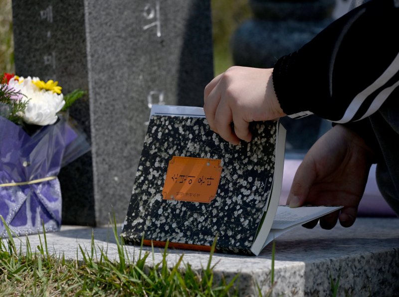 [광주=뉴시스] 김혜인 기자=광주 5·18민주화운동 45주년 엿새를 앞둔 12일 오전 광주 북구 국립 5·18민주묘지에서 학생들이 한강 작가의 '소년이 온다' 책 주인공 '동호' 실존 인물인 문재학 열사의 묘소를 참배하던 중 소설 '소년이 온다'를 제단에 바치고 있다. 2025.05.12. hyein0342@newsis.com