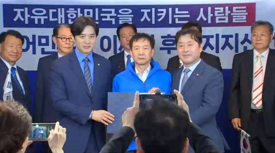 김동렬 박근혜 서포터즈 회장(가운데)이 19일 서울 여의도 더불어민주당 당사에서 당 선대위 전국민화합위원회 상임위원장에 임명된 뒤 파란색 점퍼를 입은 모습. 사진=JTBC