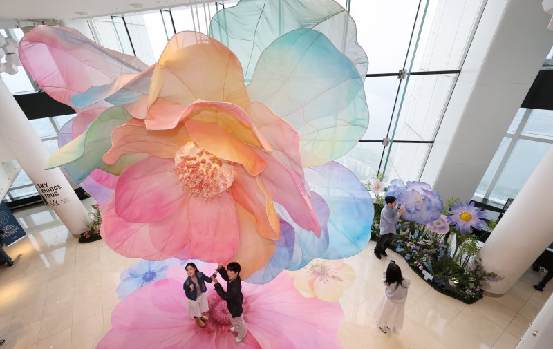 20일 서울 송파구 롯데월드타워 전망대 서울스카이에 마련된 플라워 체험형 공간인 '블루밍 유니버스: 빅플라워' 앞에서 모델들이 포즈를 취하고 있다. 2025.5.20/뉴스1 ⓒ News1 박지혜 기자