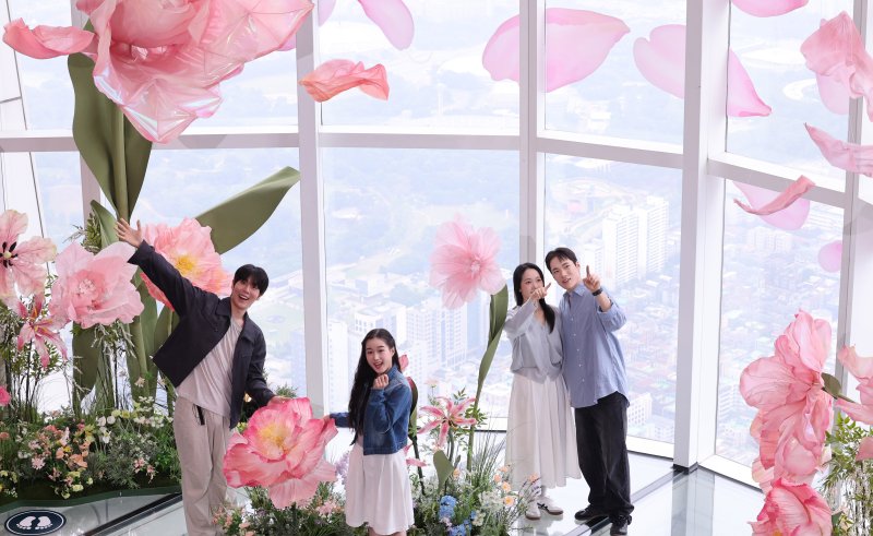 20일 서울 송파구 롯데월드타워 전망대 서울스카이에 마련된 플라워 체험형 공간인 '블루밍 유니버스: 빅플라워' 앞에서 모델들이 포즈를 취하고 있다. 2025.5.20/뉴스1 ⓒ News1 박지혜 기자