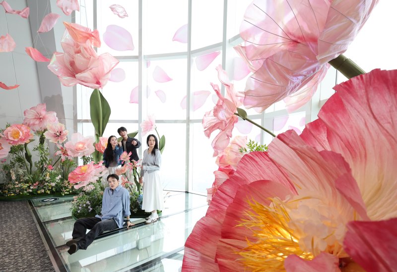 20일 서울 송파구 롯데월드타워 전망대 서울스카이에 마련된 플라워 체험형 공간인 '블루밍 유니버스: 빅플라워' 앞에서 모델들이 포즈를 취하고 있다. 2025.5.20/뉴스1 ⓒ News1 박지혜 기자