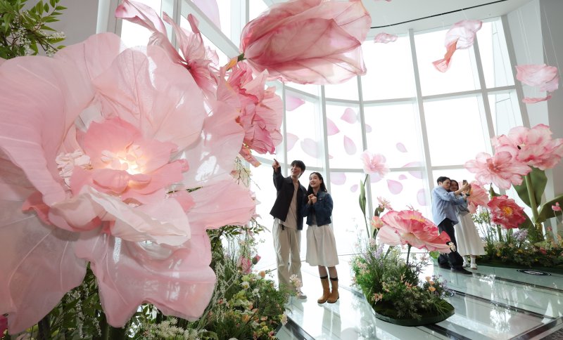 20일 서울 송파구 롯데월드타워 전망대 서울스카이에 마련된 플라워 체험형 공간인 '블루밍 유니버스: 빅플라워' 앞에서 모델들이 포즈를 취하고 있다. 2025.5.20/뉴스1 ⓒ News1 박지혜 기자