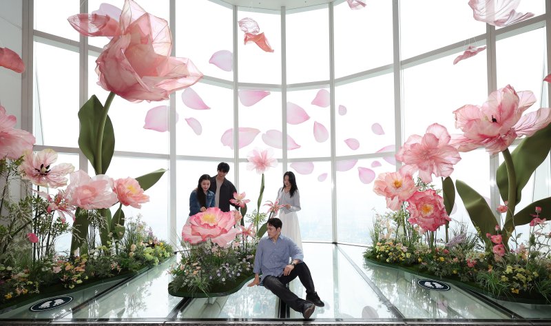 20일 서울 송파구 롯데월드타워 전망대 서울스카이에 마련된 플라워 체험형 공간인 '블루밍 유니버스: 빅플라워' 앞에서 모델들이 포즈를 취하고 있다. 2025.5.20/뉴스1 ⓒ News1 박지혜 기자