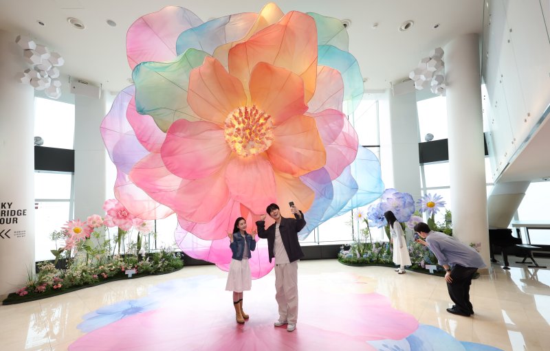 20일 서울 송파구 롯데월드타워 전망대 서울스카이에 마련된 플라워 체험형 공간인 '블루밍 유니버스: 빅플라워' 앞에서 모델들이 포즈를 취하고 있다. 2025.5.20/뉴스1 ⓒ News1 박지혜 기자