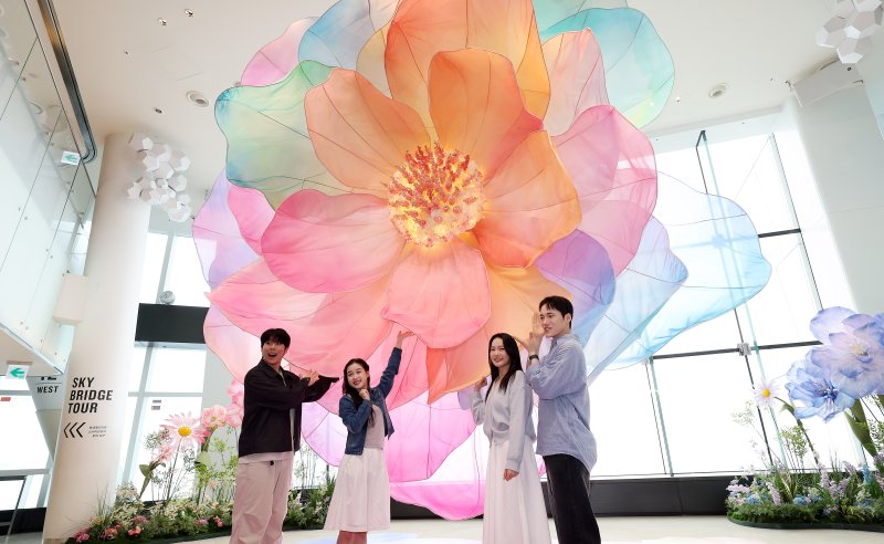 20일 서울 송파구 롯데월드타워 전망대 서울스카이에 마련된 플라워 체험형 공간인 '블루밍 유니버스: 빅플라워' 앞에서 모델들이 포즈를 취하고 있다. 2025.5.20/뉴스1 ⓒ News1 박지혜 기자