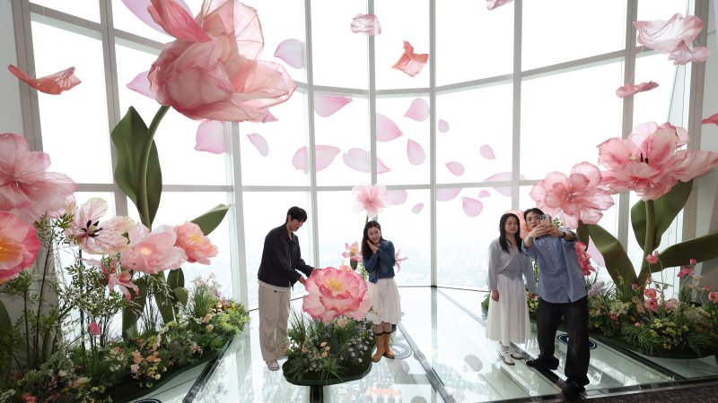 20일 서울 송파구 롯데월드타워 전망대 서울스카이에 마련된 플라워 체험형 공간인 '블루밍 유니버스: 빅플라워' 앞에서 모델들이 포즈를 취하고 있다. 2025.5.20/뉴스1 ⓒ News1 박지혜 기자