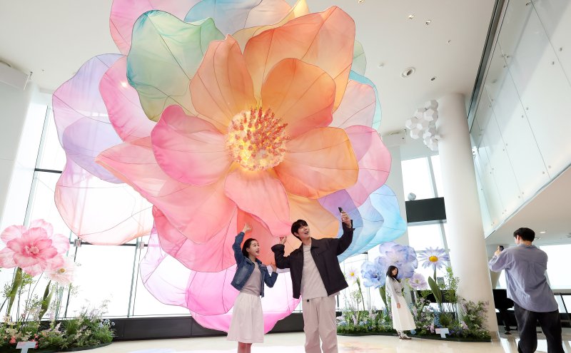 20일 서울 송파구 롯데월드타워 전망대 서울스카이에 마련된 플라워 체험형 공간인 '블루밍 유니버스: 빅플라워' 앞에서 모델들이 포즈를 취하고 있다. 2025.5.20/뉴스1 ⓒ News1 박지혜 기자
