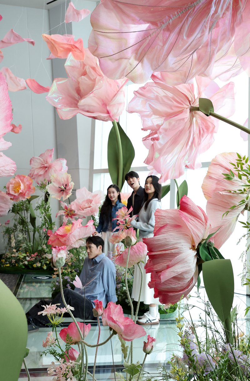 20일 서울 송파구 롯데월드타워 전망대 서울스카이에 마련된 플라워 체험형 공간인 '블루밍 유니버스: 빅플라워' 앞에서 모델들이 포즈를 취하고 있다.. 2025.5.20/뉴스1 ⓒ News1 박지혜 기자