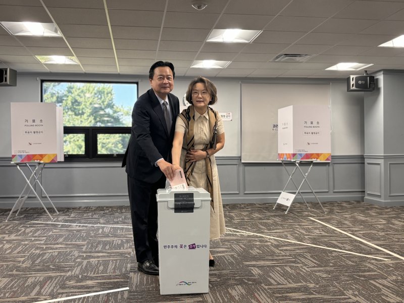 [워싱턴=뉴시스]이윤희 특파원 = 20일(현지 시간) 미국 버지니아주 알렉산드리아 코리안커뮤니티센터에 마련된 제21대 대통령선거 재외투표 투표소에서 조현동 주미대사 부부가 투표용지를 투표함에 넣기 전 취재진을 바라보고 있다. 이번 대선 재외선거는 이날부터 오는 25일까지 전 세계 118개국 223개 투표소에서 진행된다. 2025.05.21.