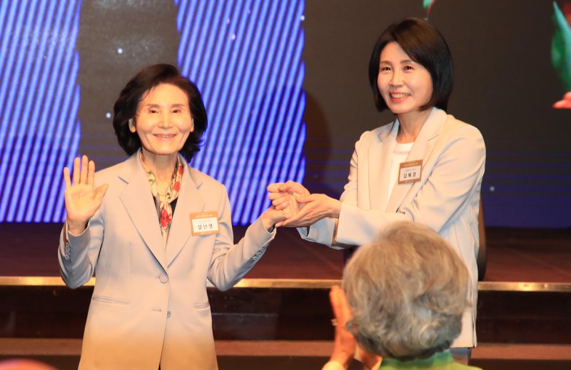 [서울=뉴시스] 조성봉 기자 = 이재명 더불어민주당 대선 후보의 부인 김혜경 여사와 김문수 국민의힘 대선후보의 부인 설난영(왼쪽) 여사가 12일 서울 중구 신라호텔에서 열린 중앙신도회 창립 70주년 기념식에서 손을 맞잡고 있다. (사진=조계종 제공) 2025.05.13. photo@newsis.com