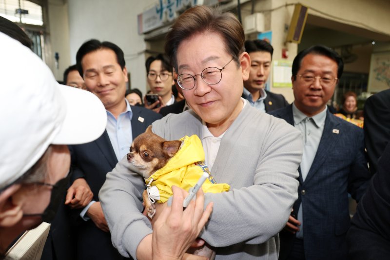 [강진=뉴시스] 조성우 기자 = 민심을 청취하는 '경청 투어'에 나선 이재명 더불어민주당 대선후보가 11일 전남 강진군 강진오감통시장에서 한 주민의 강아지를 안아보고 있다. 2025.05.11. xconfind@newsis.com