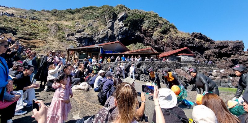 [서귀포=뉴시스] 우장호 기자 = 완연한 봄날씨를 보인 6일 오후 제주 도내 대표적인 관광지 성산일출봉 해변에서 관광객들이 제주 해녀 공연을 관람하고 있다. 2025.04.06. woo1223@newsis.com