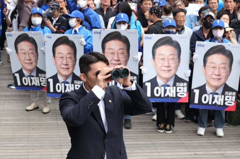 [부천=뉴시스] 조성봉 기자 = 이재명 더불어민주당 대선 후보가 24일 경기 부천 원미구 부천역 북부 광장에서 열린 유세를 하고 있는 가운데 경호원이 망원경으로 주변을 탐색하고 있다. 2025.05.24.suncho21@newsis.com
