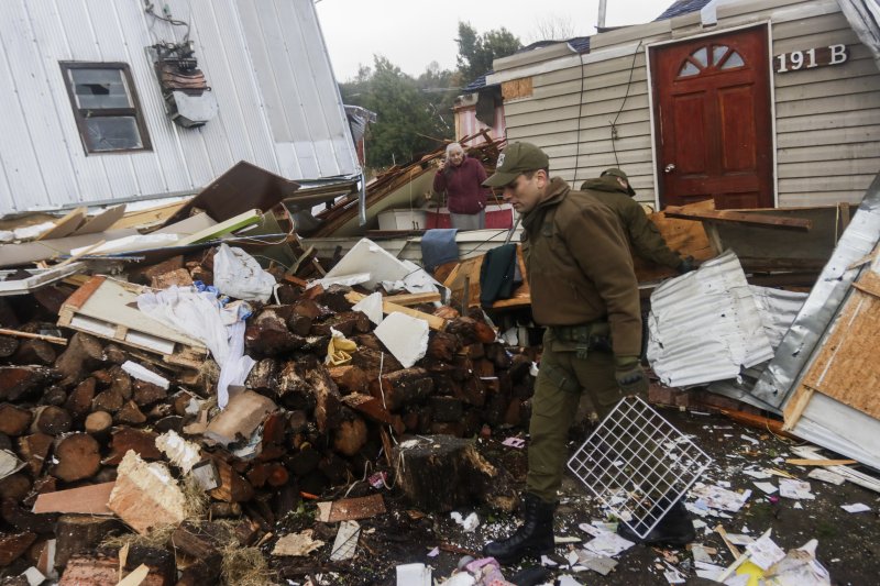 A police officer walks amid the debris the day after a tornado hit Puerto Varas, Chile, Monday, May 26, 2025. (AP Photo/Patricio Aguayo)