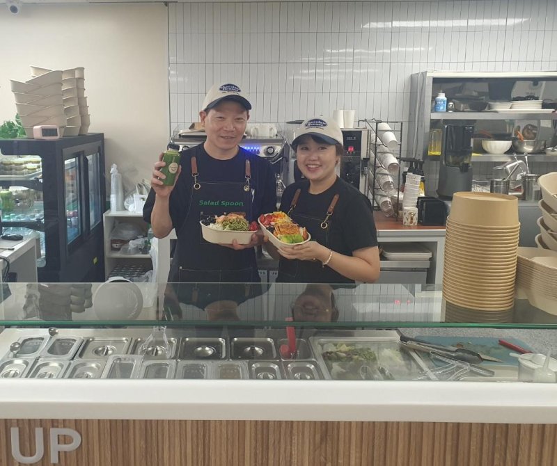 지난 27일 부산 서구 동아대메이저 바카라사이트 굿모닝 식당가에 위치한 샐러드스푼의 사장 부부인 정은배씨(왼쪽부터)와 이혜지씨가 샐러드와 수제 음료를 든 채 포즈를 취하고 있다. 사진=최승한 기자