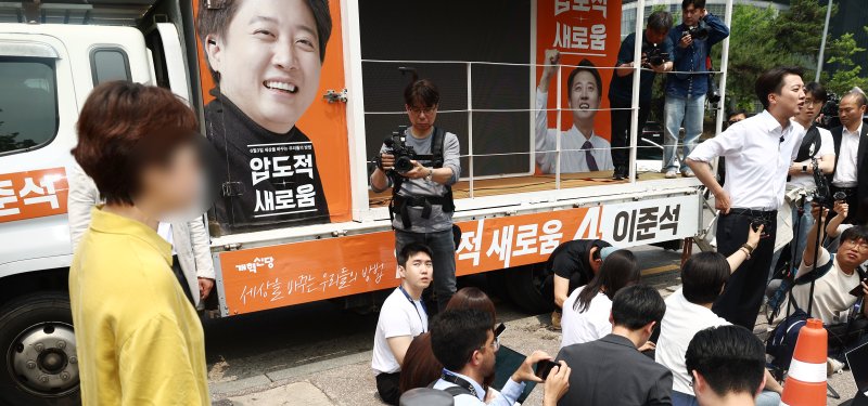 이준석 개혁신당 대통령 후보가 28일 서울 영등포구 여의도공원에서 유세를 마치고 취재진 질의에 답변하고 있는 가운데 한 시민이 이 후보가 전날 토론회에서 여성 신체를 묘사 발언을 한 것에 대해 항의하고 있다. 2025.5.28/뉴스1 ⓒ News1 김민지 기자