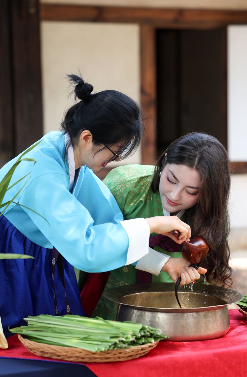 [서울=뉴시스] 김선웅 기자 = 단오(음력 5월 5일)를 이틀 앞둔 29일 서울 종로구 국립민속박물관 오촌댁 앞마당에서 열린 단오 세시행사에서 외국인 관광객이 창포물 머리감기 체험을 하고 있다. 2025.05.29. mangusta@newsis.com