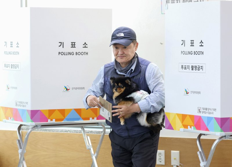 [서울=뉴시스] 김진아 기자 = 제21대 대통령선거 사전투표가 시작된 29일 서울 중구 중림동주민센터에 마련된 사전투표소에서 한 유권자가 강아지와 투표를 하고 있다. 2025.05.29. bluesoda@newsis.com