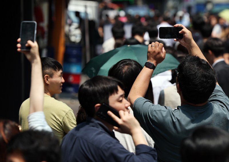 제21대 대통령선거 사전투표 첫 날인 29일 서울 중구 소공동주민센터에 마련된 투표소에서 직장인들이 점심시간 투표를 위해 대기하며 길게 늘어선 투표 인파를 스마트폰에 담고 있다. 2025.5.29/뉴스1 ⓒ News1 오대일 기자