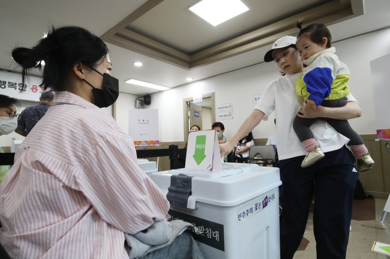제21대 대통령선거 사전투표 첫날인 29일 부산 남구 용호4동주민센터 마련된 사전투표소에서 유권자가 아이를 안고 투표하고 있다. 2025.5.29/뉴스1 ⓒ News1 윤일지 기자