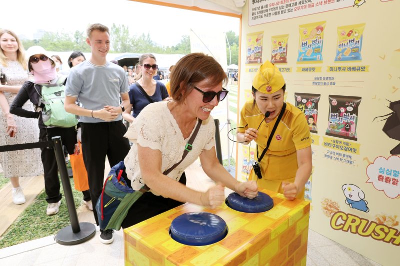 파이낸셜뉴스가 29일 서울 중구 서울광장에서 주최한 '2025 서울식품유통대전(K푸드쇼)' 이틀째 행사에서 한 외국인이 오뚜기 부스 이벤트를 체험하며 즐거운 시간을 보내고 있다.