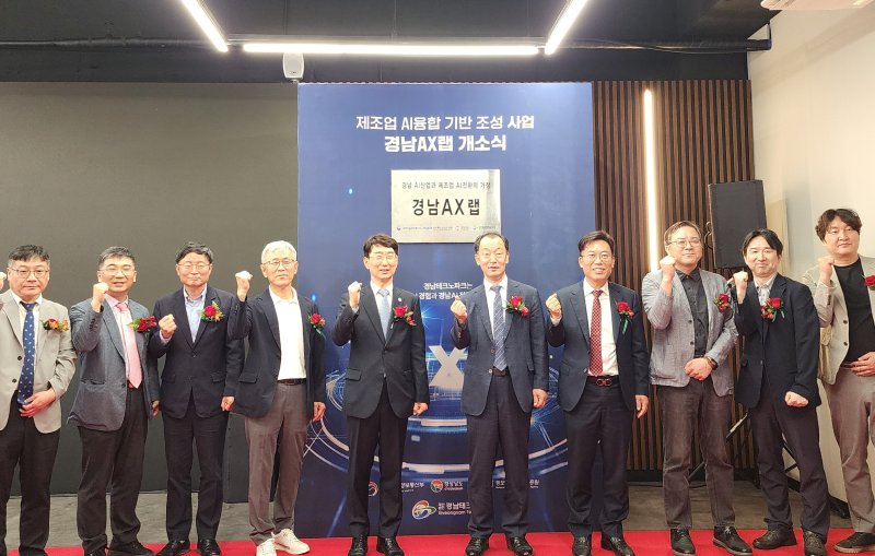[창원=뉴시스]29일 경남 창원스마트혁신지원센터에서 열린 제조 산업과 인공지능 기술 접목·확산 거점기관 '경남 AX랩' 개소식 참석자들이 현판을 제막한 후 기념촬영하고 있다.(사진=경남도 제공) 2025.05.29. photo@newsis.com