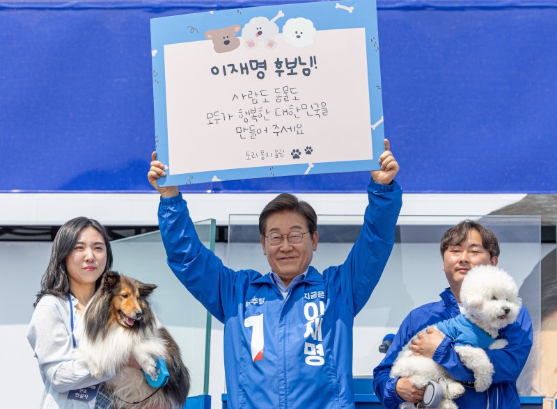 [춘천=뉴시스] 조성우 기자 = 이재명 더불어민주당 대선후보가 30일 오후 강원 춘천시 춘천역 광장에서 열린 집중유세에서 반려견 토리, 뭉치의 편지 판넬을 들어 보이고 있다. (공동취재) 2025.05.30. photo@newsis.com