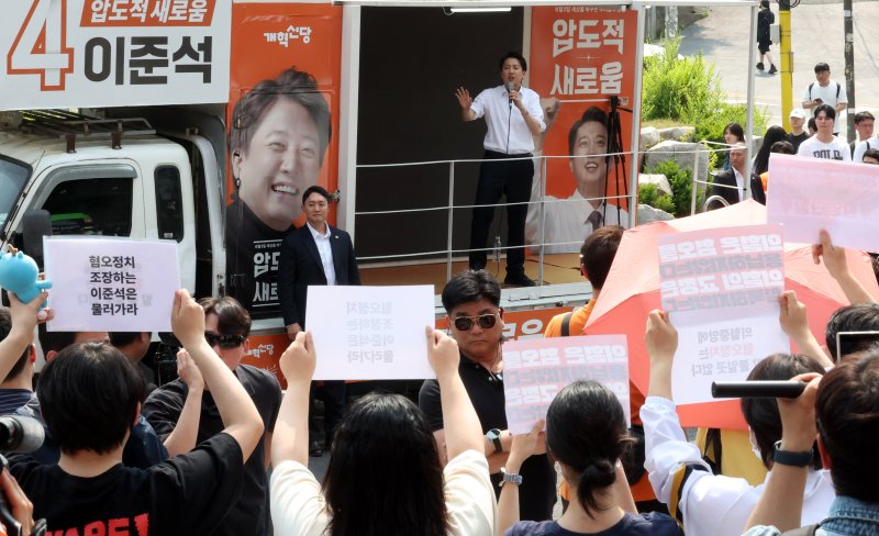 [서울=뉴시스] 추상철 기자 = 30일 오후 서울 동작구 중앙대학교 후문에서 대학생들이 유세를 펼치는 이준석 개혁신당 대선후보를 향해 혐오 발언 규탄 피켓을 들어 보이고 있다. 2025.05.30. scchoo@newsis.com