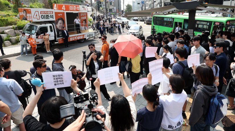 [서울=뉴시스] 추상철 기자 = 30일 오후 서울 동작구 중앙대학교 후문에서 대학생들이 유세를 펼치는 이준석 개혁신당 대선후보를 향해 혐오 발언 규탄 피켓을 들어 보이고 있다. 2025.05.30. scchoo@newsis.com