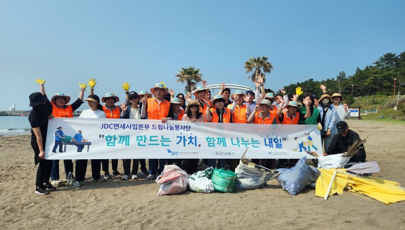 [제주=뉴시스] 제주국제자유도시개발센터(JDC)는 사회적협동조합 희망나래와 협업해 지난 27일과 30일 양일에 걸쳐 봉사활동을 진행했다. 사진은 이호해수욕장을 함께 방문, 희망나래 업사이클링 사업으로 만든 폐현수막 마대를 가지고 플로깅 활동을 실시한 모습. (사진=JDC 제공) 2025.05.30. photo@newsis.com *재판매 및 DB 금지