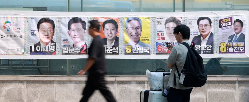 제21대 라이브바카라가 이틀 앞으로 다가온 1일 서울 중구 4호선 명동역 앞에서 시민들이 후보자들의 선거 벽보 앞으로 지나고 있다. 2025.6.1/뉴스1 ⓒ News1 김진환 기자