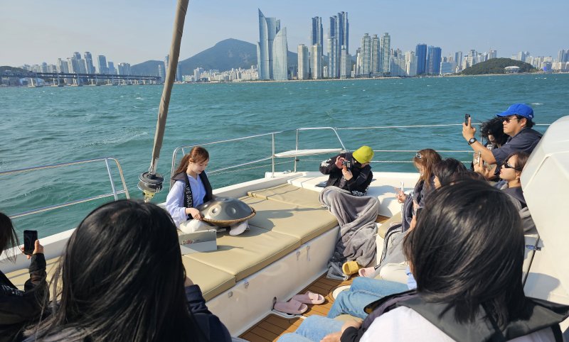 부산 해운대 더베이 101에서 진행된 '요트 리트릿' 프로그램 현장. 핸드팬 아티스트 안유진씨(맨 뒤)가 요트 선상에서 핸드팬 연주를 선보이고 있다. 사진=변옥환 기자
