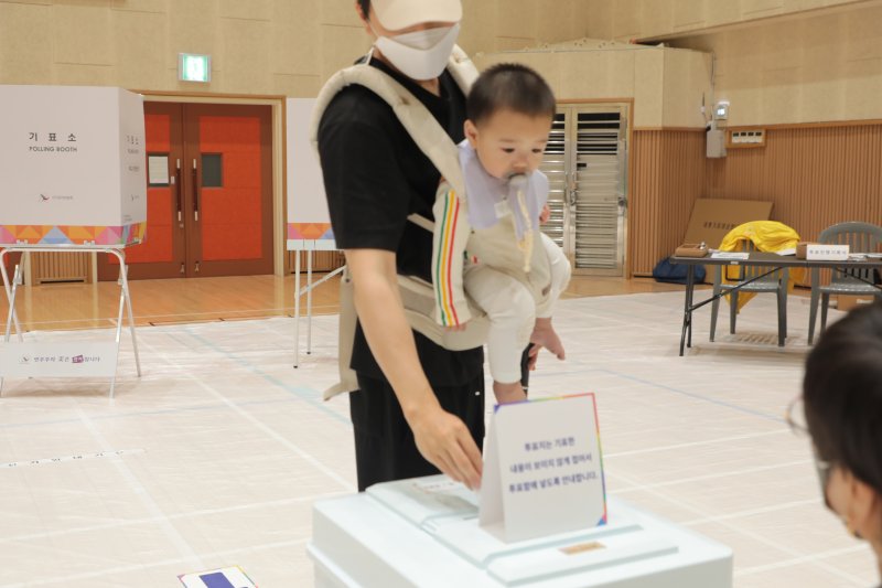 21대 대통령선거 본투표일인 3일 울산 북구 고헌초등학교에 마련된 투표소에서 한 시민이 자녀를 안고 투표하고 있다. 2025.6.3/뉴스1 ⓒ News1 김세은 기자
