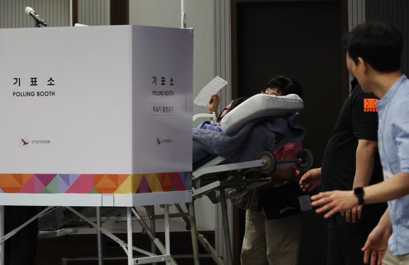제21대 대통령 선거일인 3일 서울 용산구 중부기술교육원에 마련된 한남동 제3투표소에서 한 환자가 보호자와 구급대원의 도움을 받아 투표에 참여하고 있다. 연합바카라사이트 정보