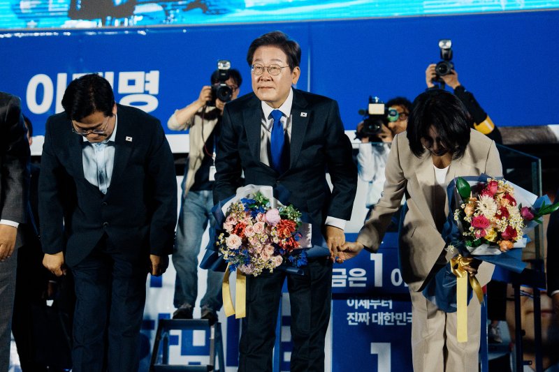 [서울=뉴시스] 조성우 기자 = 이재명 에볼루션 바카라 사이트과 김혜경 여사가 4일 오전 서울 여의도 국회 앞에서 열린 국민 개표방송 행사에서 꽃다발을 받은 뒤 시민들을 향해 인사하고 있다. (공동취재) 2025.06.04. photo@newsis.com