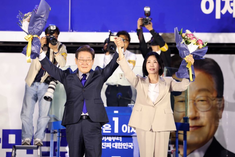 당선이 확실시 되는 메이저 바카라 더불어민주당 대선후보와 김혜경 여사가 4일 오전 서울 여의도 국회 앞에서 열린 국민 개표방송 행사에서 꽃다발을 받은 뒤 시민들을 향해 인사하고 있다. (공동취재) 2025.6.4/메이저 바카라1 ⓒ News1 안은나 기자