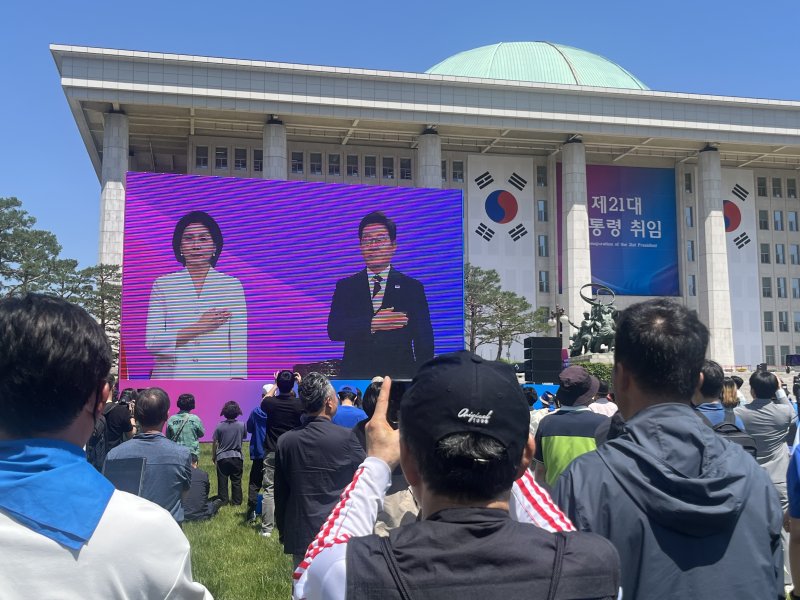 이재명 21대 대통령 취임식이 열리는 4일 오전 서울 여의도 국회의사당 잔디광장에 시민들이 모여 취임 선서를 지켜보고 있다. / 뉴스1 김종훈 기자