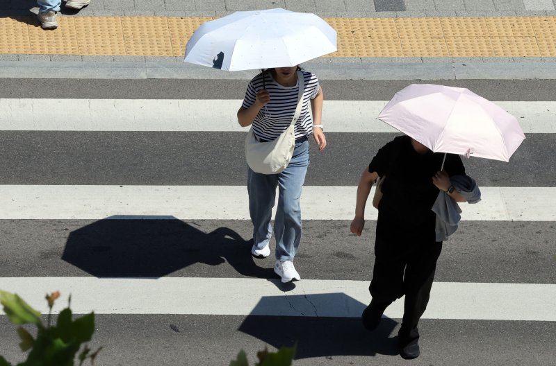 [부산=뉴시스] 하경민 기자 = 무더운 날씨를 보인 4일 부산 동구 부산역 광장 횡단보도에서 시민들이 양산을 쓰고 길을 건너고 있다. 2025.06.04. yulnetphoto@newsis.com