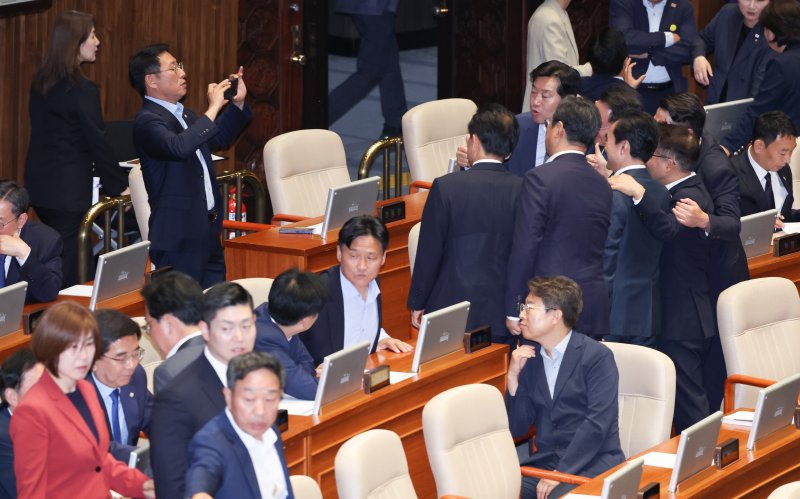 더불어민주당 의원들이 5일 오후 서울 여의도 국회 본회의장에서 기념 촬영하는 가운데 국민의힘 의원들이 입장하고 있다. 2025.6.5/뉴스1 ⓒ News1 안은나 기자