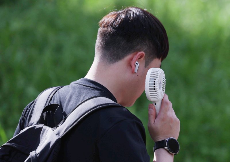 [서울=뉴시스] 김진아 기자 = 여름 기운이 돌기 시작하는 절기 '소만'인 21일 서울 종로구 일대에서 반팔을 입은 시민이 손선풍기를 사용하며 출근하고 있다. 사진은 본 기사와 관계 없음. 2025.05.21. bluesoda@newsis.com