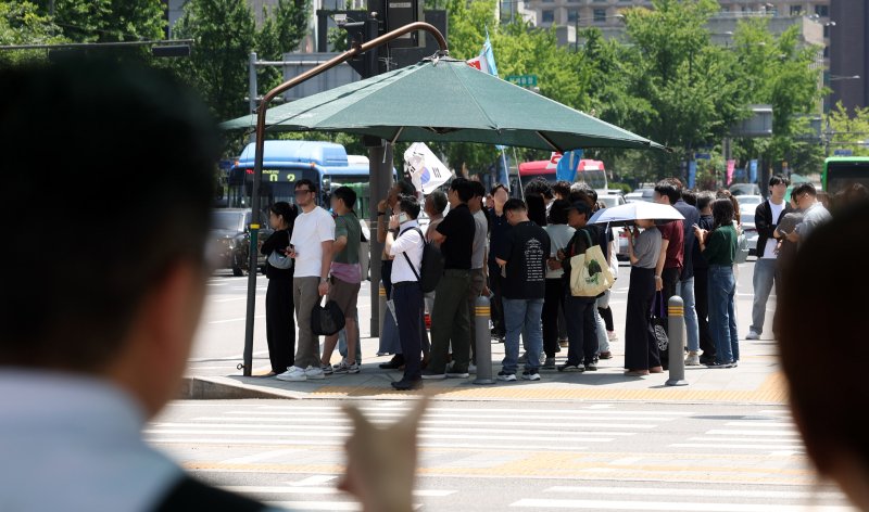 [서울=뉴시스] 추상철 기자 = 절기상 망종에 초여름 날씨가 이어진 5일 오후 서울 종로구 세종대로사거리에서 시민들이 그늘막 아래에 모여 횡단보도 신호를 기다리고 있다. 2025.06.05. scchoo@newsis.com