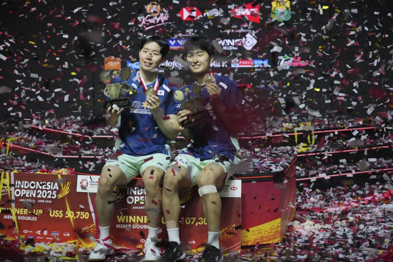 [자카르타=AP/뉴시스] 김원호(오른쪽)와 서승재가 8일(현지 시간) 인도네시아 자카르타 이스토라 스타디움에서 열린 2025 세계배드민턴연맹(BWF) 월드투어 슈퍼 1000 인도네시아오픈 남자복식 정상에 올라 금메달과 트로피를 들고 포즈를 취하고 있다. 김원호-서승재는 결승에서 사바르 카르야만 구타마-모 레자 파흘레비 이스파하니 조(인도네시아)에 2-1(18-21 21-19 21-12)로 역전승을 거두고 우승을 차지했다. 2025.06.09.