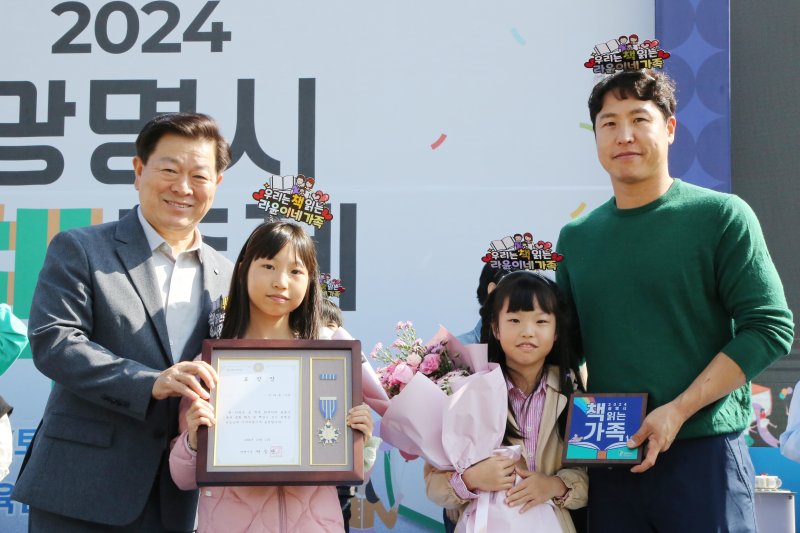 [광명=뉴시스]박승원 광명시장(사진 왼쪽 첫 번째)이 2024년 10월 광명시민체육관 잔디광장에서 열린 '2024 광명시 책축제'에서 독서문화 실천 가족에게 표창장을 수여하고 기념촬영을 하고 있다.(사진=광명시 제공)2025.06.11.photo@newsis.com