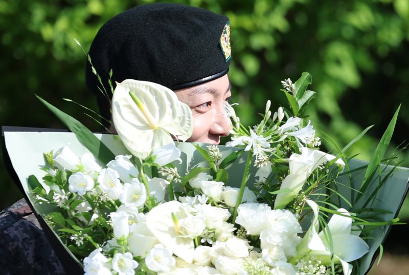 방탄소년단(BTS)의 정국이 11일 오전 경기도 연천군 연천공설운동장에서 군복무를 마친 뒤 꽃다발을 받고 수줍은 미소를 짓고 있다. ⓒ News1 권현진 기자