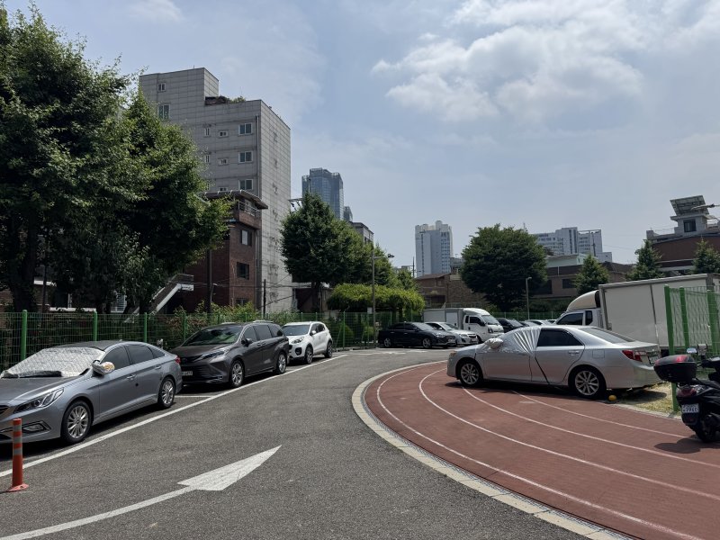 [서울=뉴시스]]김지윤 인턴기자 = 서울 광진구 화양초등학교 전경. 2023년 폐교된 이후 2년째 방치 중인 이 부지는 현재 임시 주차장으로 활용되고 있다. 사진은 화양초 운동장 한편에 차량 수대가 주차돼 있는 모습. 2025.06.12