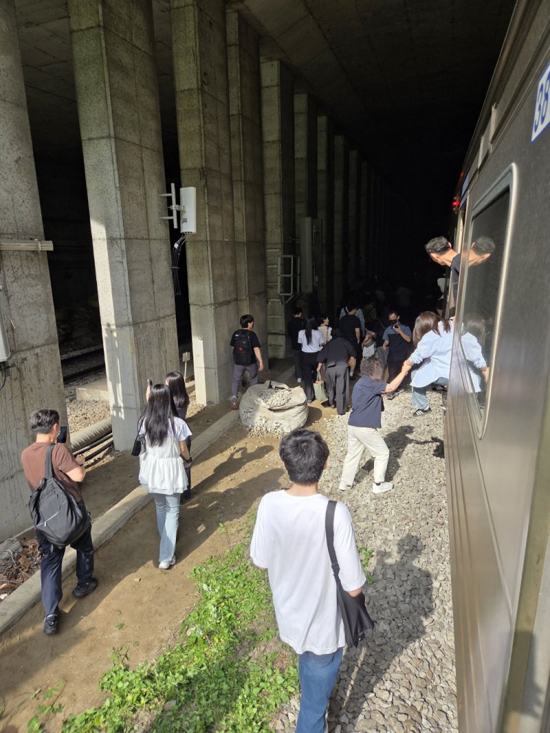 13일 오전 경의중앙선 신촌역 인근에서 사다리차 전도사고가 발생해 가좌역~신촌역 구간이 양방향 통제된 가운데 서울역행 경의중앙선 열차에 탑승한 승객들이 열차에서 내려 선로를 따라 대피하고 있다. (독자 제공, 재판매 및 DB금지)