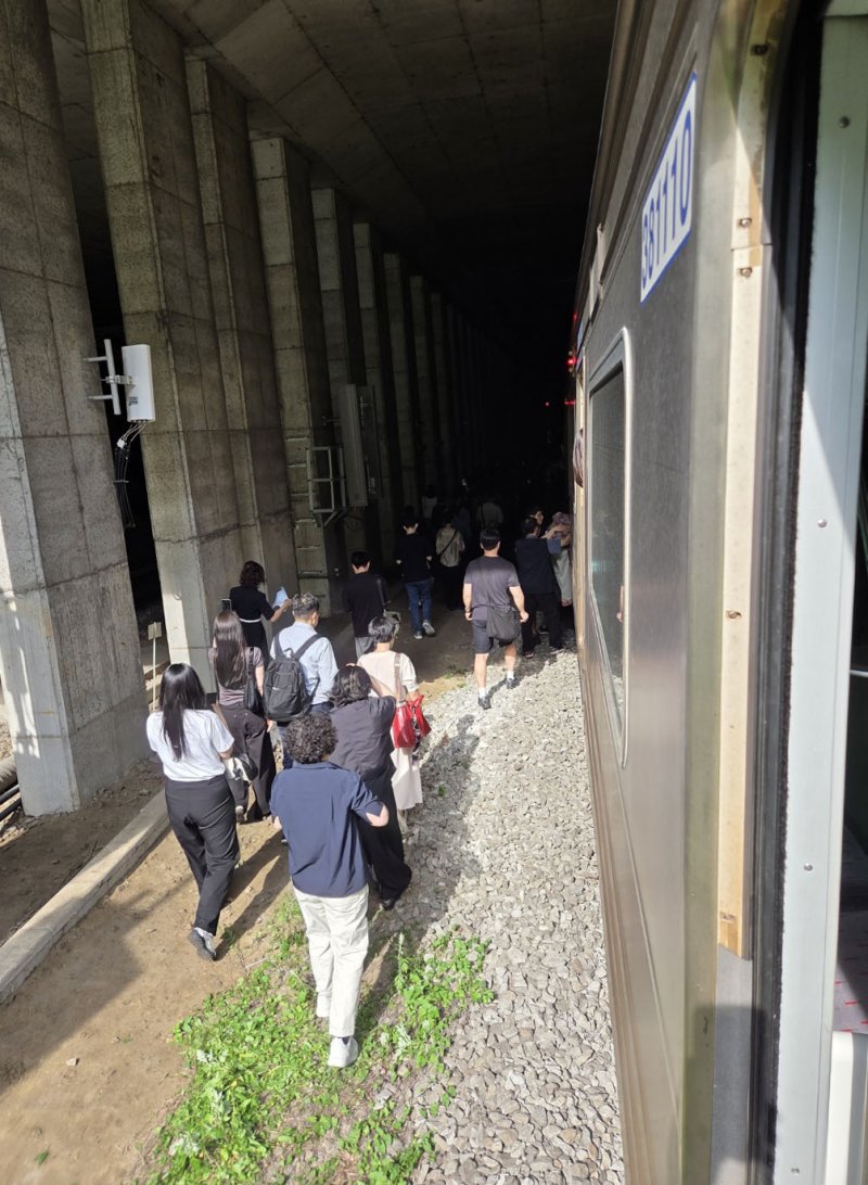 13일 오전 경의중앙선 신촌역 인근에서 사다리차 전도사고가 발생해 가좌역~신촌역 구간이 양방향 통제된 가운데 서울역행 경의중앙선 열차에 탑승한 승객들이 열차에서 내려 선로를 따라 대피하고 있다. (독자 제공, 재판매 및 DB금지)