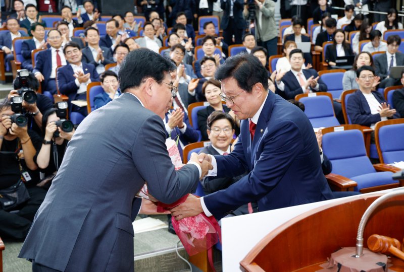 국민의힘 신임 원내대표로 선출된 송언석 의원(왼쪽)이 16일 오후 서울 여의도 국회에서 열린 의원총회에서 박형수 선관위원장으로부터 꽃다발을 받고 있다. 2025.6.16/뉴스1 ⓒ News1 안은나 기자