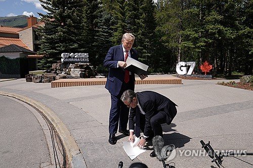 무역협정문 떨어뜨린 트럼프 미국 대통령과 이를 줍는 스타머 영국 총리 (출처=연합뉴스)