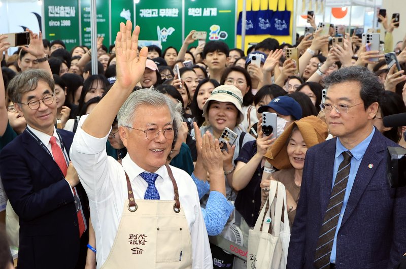 문재인 전 대통령이 18일 오후 서울 강남구 삼성동 코엑스에서 열린 2025 서울국제도서전 평산책방 부스에서 앞치마를 두르고 나와 방문객들에게 인사하고 있다. 2025.6.18/뉴스1 ⓒ News1 박정호 기자